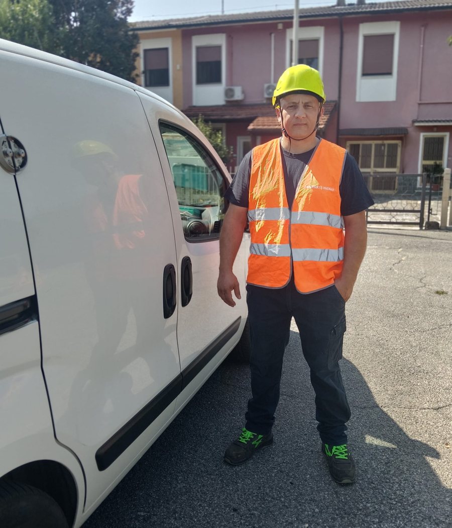 Gabriel Calasi in casco e gilet ad alta visibilità accanto al suo furgone da lavoro